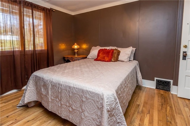 bedroom featuring wood-type flooring, visible vents, and crown molding