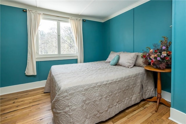 bedroom featuring ornamental molding, baseboards, and wood finished floors