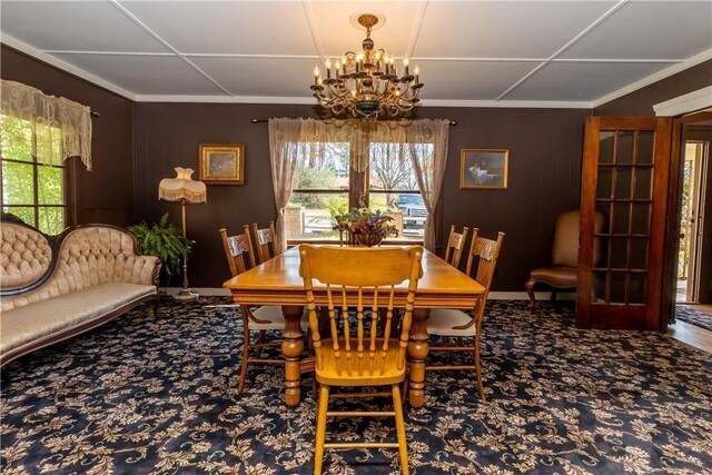 carpeted dining space with crown molding and a notable chandelier