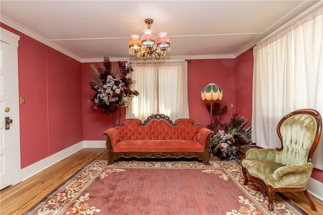 living area featuring an inviting chandelier, baseboards, ornamental molding, and wood finished floors