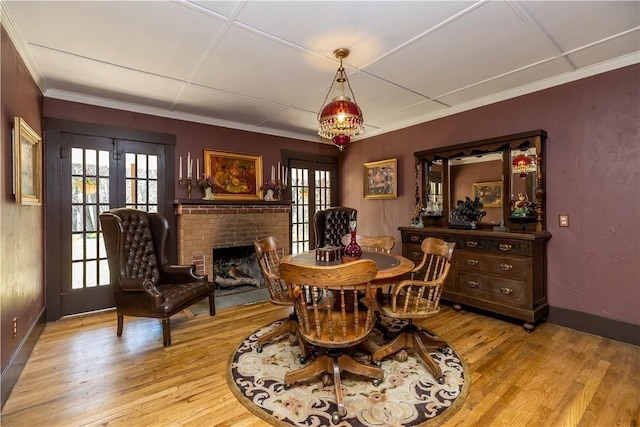 dining room with ornamental molding, a brick fireplace, wood finished floors, and baseboards