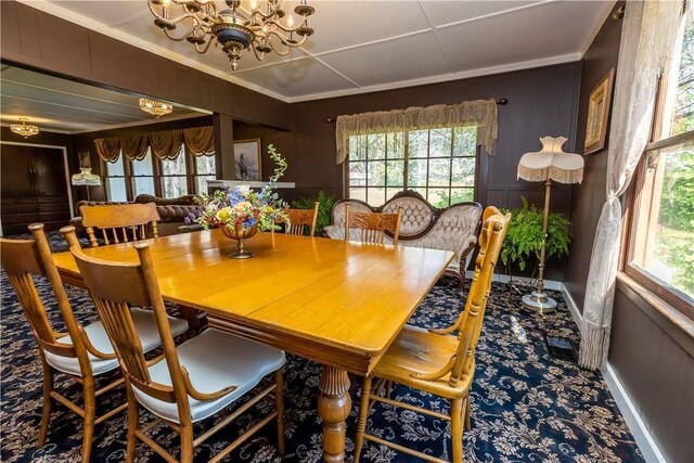 dining room with an inviting chandelier, carpet, a decorative wall, and crown molding