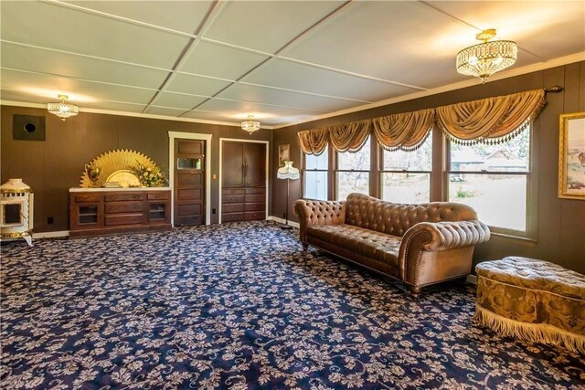 sitting room with baseboards, carpet flooring, and wooden walls