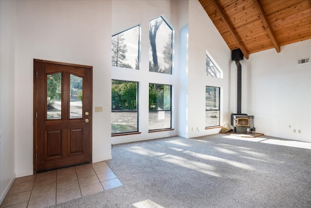 39627 Brandywine Ln, Oakhurst, CA 93644 - tiled entrance foyer with a towering ceiling, a wooden ceiling with exposed beams, a wood stove, carpet, and plenty of natural light
