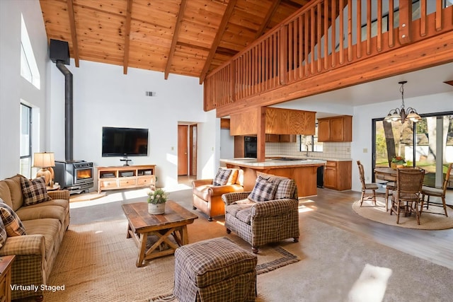 39627 Brandywine Ln, Oakhurst, CA 93644 - living area featuring a wood stove, high vaulted ceiling, a chandelier, a wood ceiling with exposed beams, and light wood-style floors