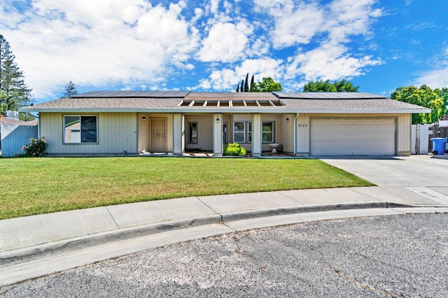 ranch-style home with a garage, a front yard, and solar panels