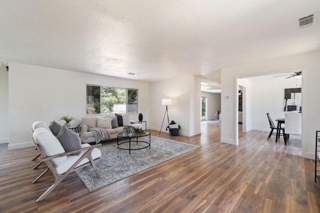 living room with dark wood-type flooring, a wealth of natural light, and ceiling fan