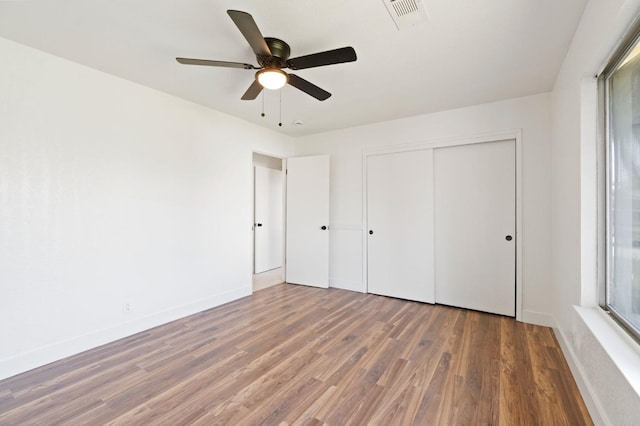 unfurnished bedroom with a closet, dark hardwood / wood-style floors, and ceiling fan