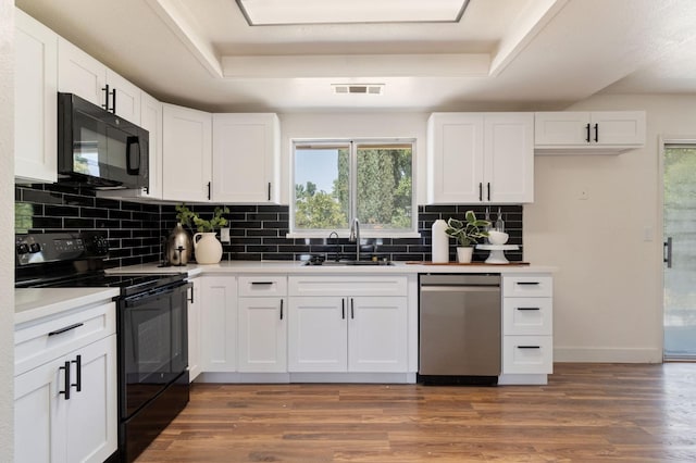 kitchen featuring sink, black appliances, a raised ceiling, and white cabinets