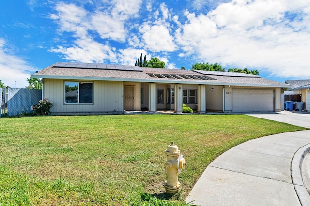 single story home featuring a garage, a front lawn, and solar panels