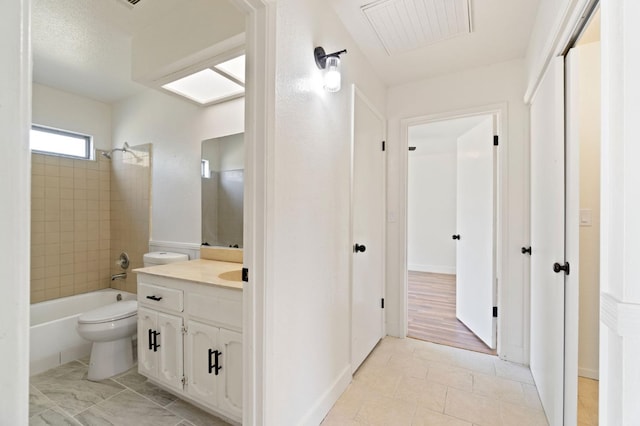 full bathroom featuring a skylight, tiled shower / bath combo, vanity, toilet, and tile patterned floors