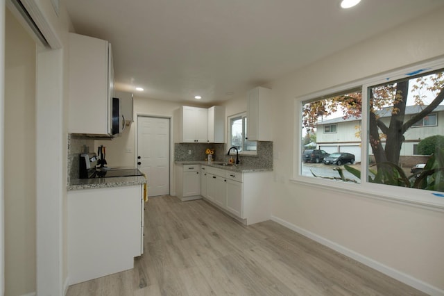 kitchen featuring sink, range, white cabinets, light hardwood / wood-style floors, and backsplash