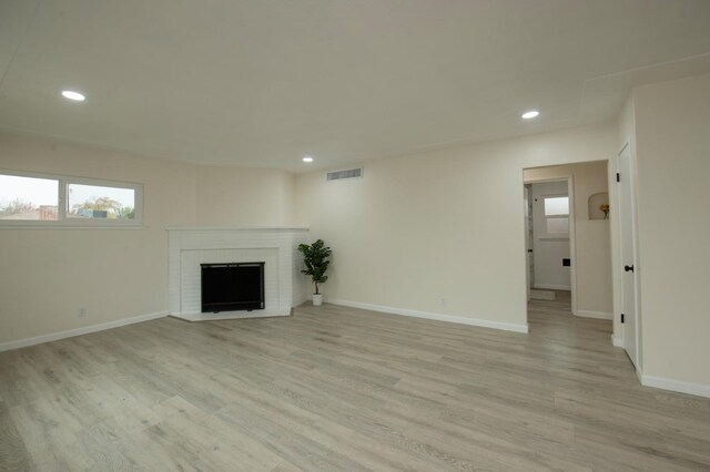 unfurnished living room with a fireplace and light wood-type flooring