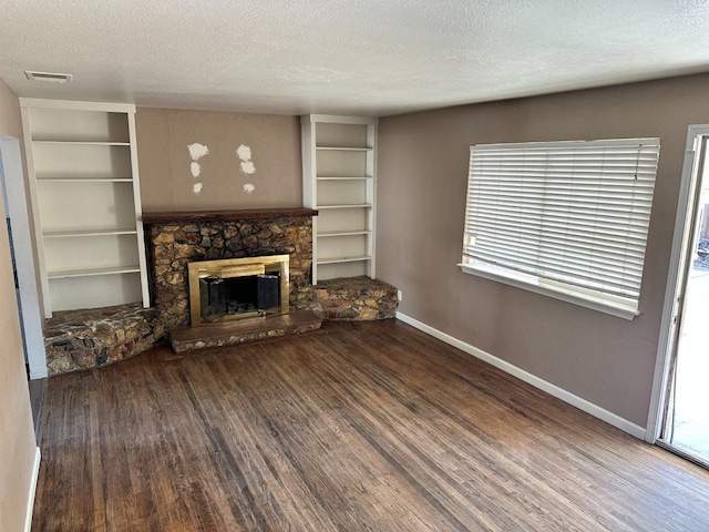 unfurnished living room with a textured ceiling, a stone fireplace, and plenty of natural light