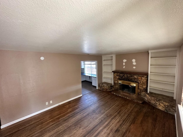 unfurnished living room featuring a fireplace, built in features, dark wood-type flooring, and a textured ceiling