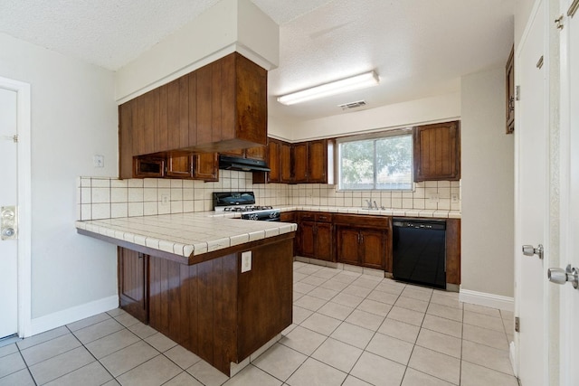 kitchen with black appliances, a textured ceiling, kitchen peninsula, and tile counters