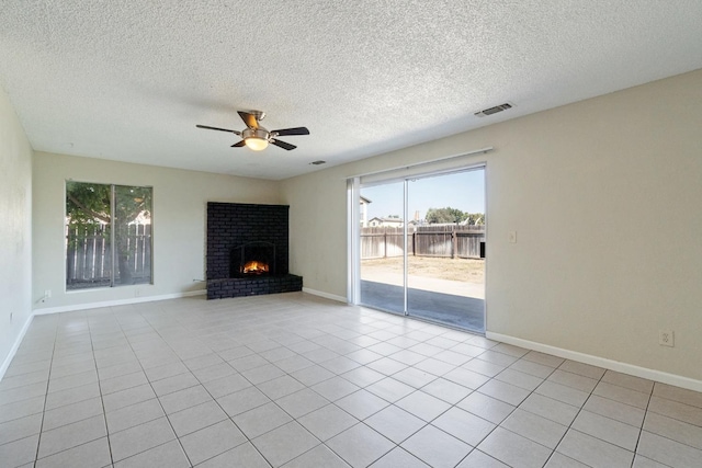 unfurnished living room featuring ceiling fan, a brick fireplace, light tile patterned flooring, and a textured ceiling