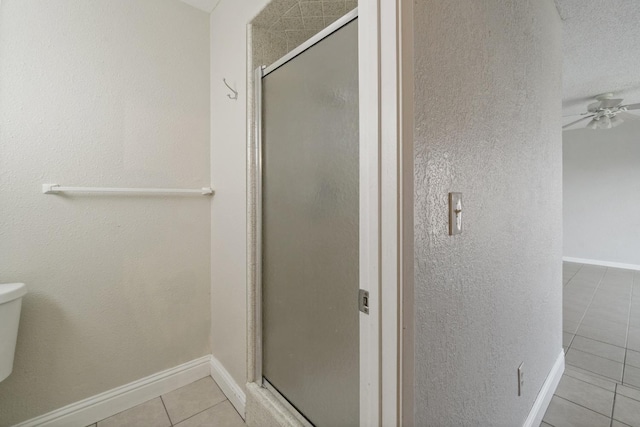 bathroom featuring toilet, a shower with door, tile patterned flooring, and ceiling fan