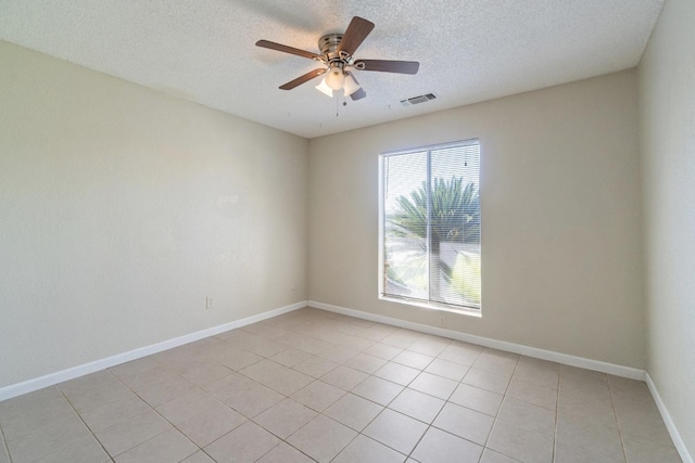 empty room with a textured ceiling, ceiling fan, and light tile patterned floors