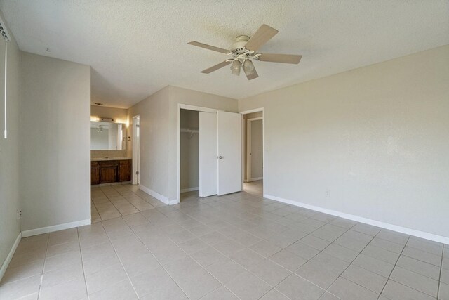 spare room with ceiling fan, a textured ceiling, and light tile patterned floors