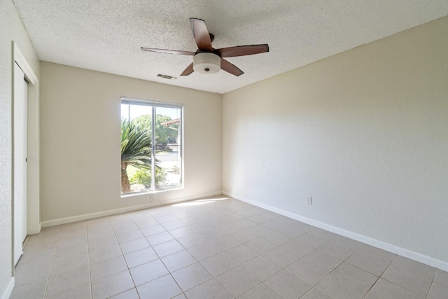 empty room with a textured ceiling, ceiling fan, and light tile patterned floors