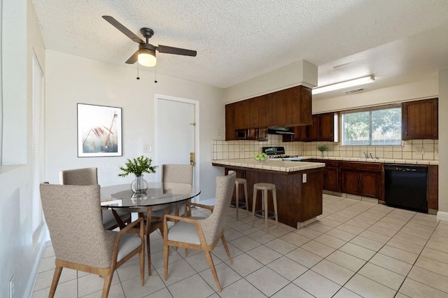 kitchen featuring kitchen peninsula, dishwasher, tile counters, decorative backsplash, and stove