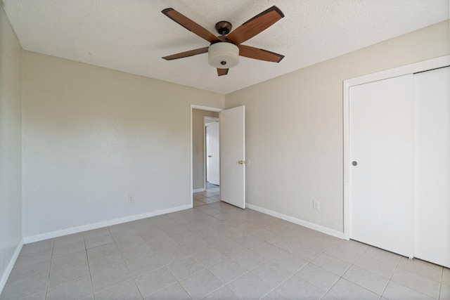 unfurnished bedroom featuring ceiling fan, a closet, a textured ceiling, and light tile patterned floors