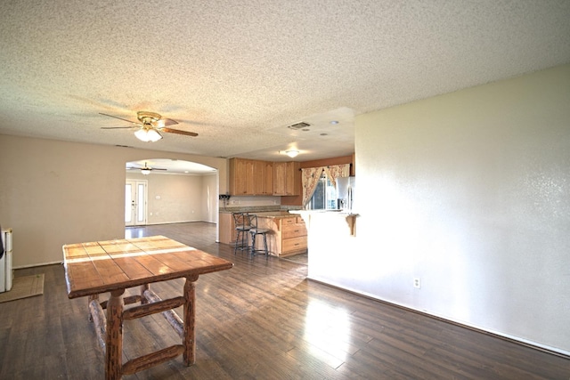 dining room with ceiling fan, dark hardwood / wood-style floors, and a textured ceiling