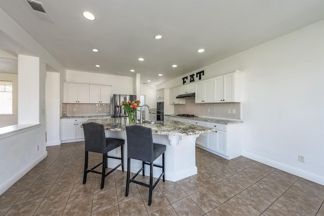 kitchen featuring a breakfast bar, a spacious island, appliances with stainless steel finishes, light stone counters, and white cabinetry