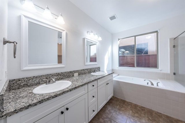 bathroom with tile patterned flooring, vanity, and tiled tub