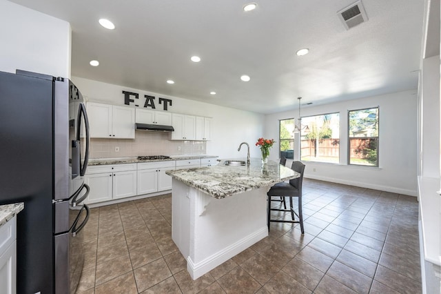 kitchen with sink, hanging light fixtures, stainless steel appliances, a breakfast bar area, and a center island with sink