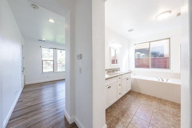 bathroom featuring tile patterned floors, vanity, and tiled bath