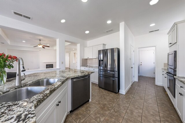 kitchen featuring white cabinets, sink, light stone countertops, and stainless steel appliances