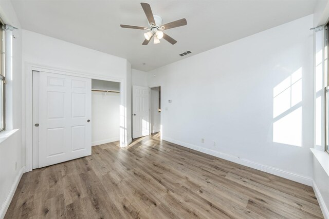 unfurnished bedroom with ceiling fan, a closet, and light hardwood / wood-style flooring