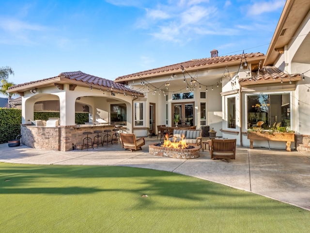 back of house featuring exterior bar, a fire pit, and a patio area