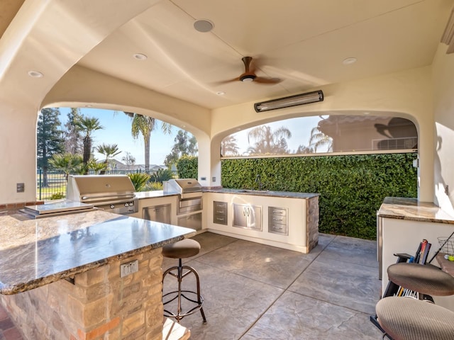 view of patio with a grill, ceiling fan, sink, and an outdoor kitchen