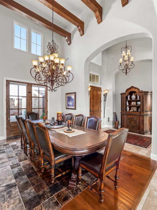 dining area featuring beamed ceiling, a towering ceiling, and a notable chandelier