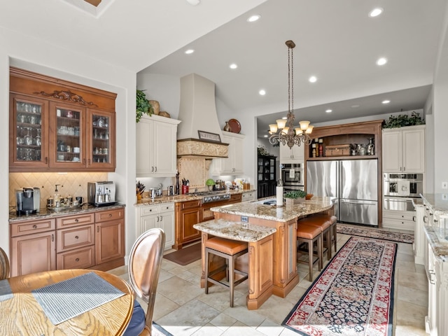 kitchen featuring hanging light fixtures, stainless steel appliances, a kitchen bar, a kitchen island, and custom exhaust hood