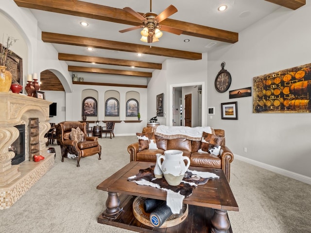 living room with ceiling fan, a fireplace, carpet floors, and beamed ceiling