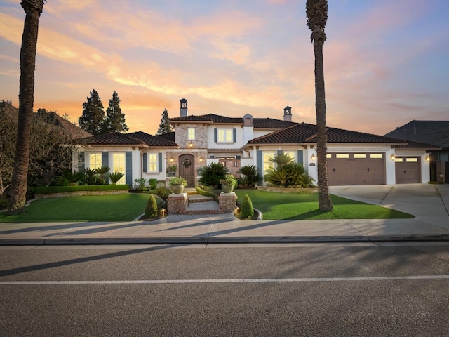 mediterranean / spanish home featuring a lawn and a garage