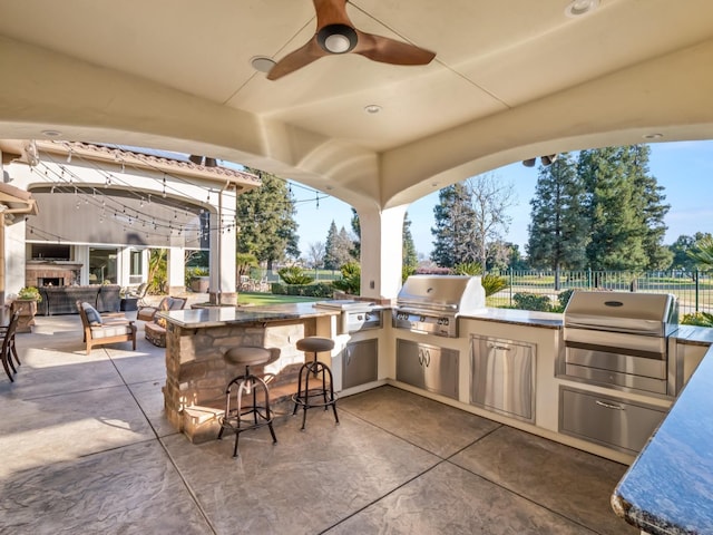 view of patio / terrace featuring an outdoor kitchen, area for grilling, a bar, and an outdoor fireplace