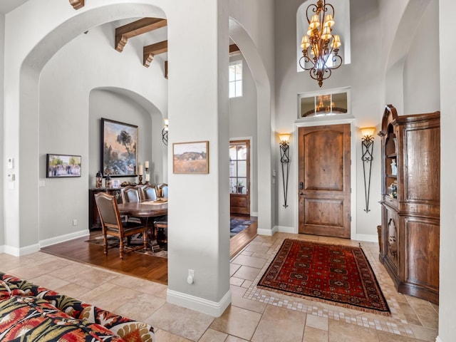 entryway with beam ceiling, a high ceiling, and a notable chandelier