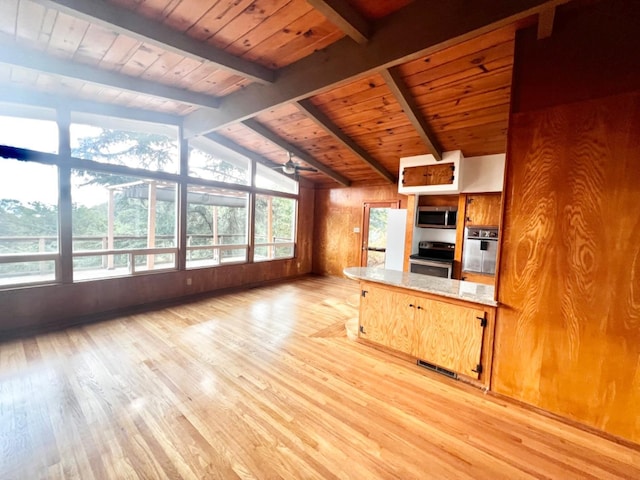 kitchen featuring wood walls, ceiling fan, stainless steel appliances, light hardwood / wood-style flooring, and lofted ceiling with beams