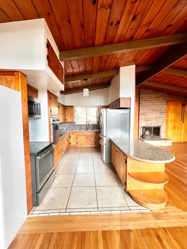 kitchen with light tile patterned floors, appliances with stainless steel finishes, decorative backsplash, lofted ceiling with beams, and sink