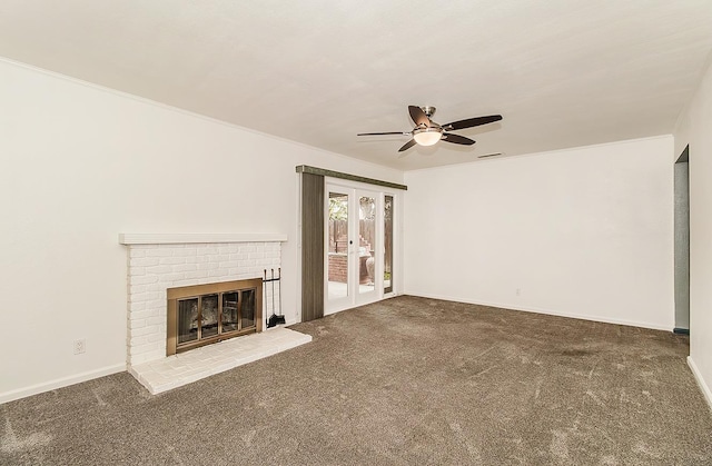 unfurnished living room with a brick fireplace, carpet, ceiling fan, french doors, and ornamental molding