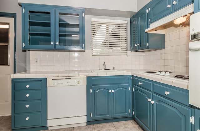 kitchen with white appliances, blue cabinetry, sink, and tile countertops