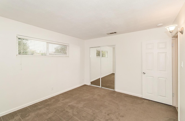 unfurnished bedroom with a closet and dark colored carpet