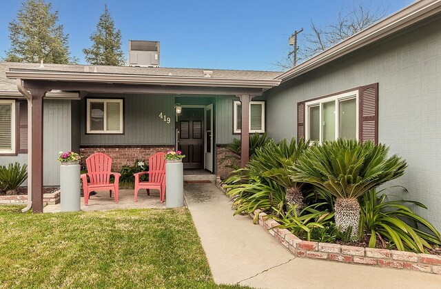 view of exterior entry featuring a yard and central air condition unit