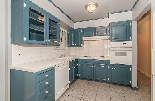 kitchen featuring white appliances, blue cabinets, and tile counters