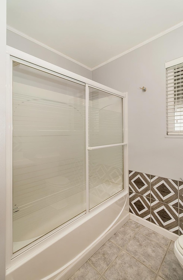 bathroom featuring toilet, tile patterned floors, ornamental molding, and enclosed tub / shower combo